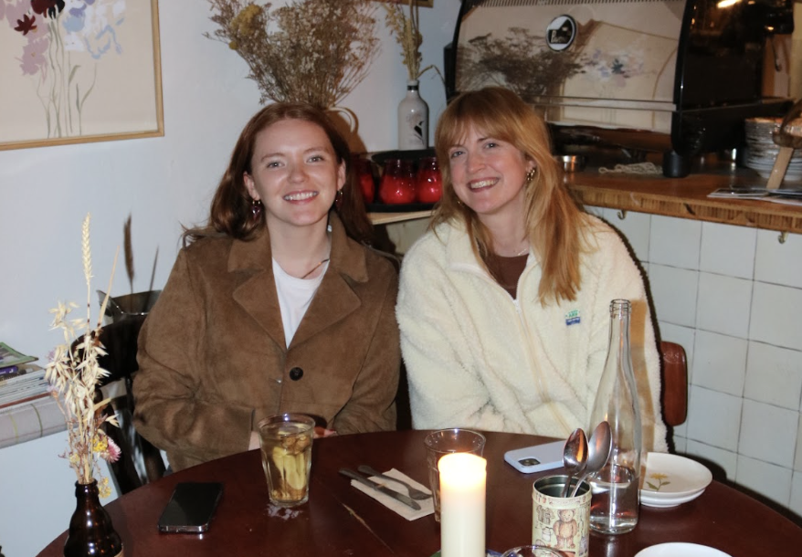 Sobremesa founders Maleen and Zara smiling together at a candlelit table