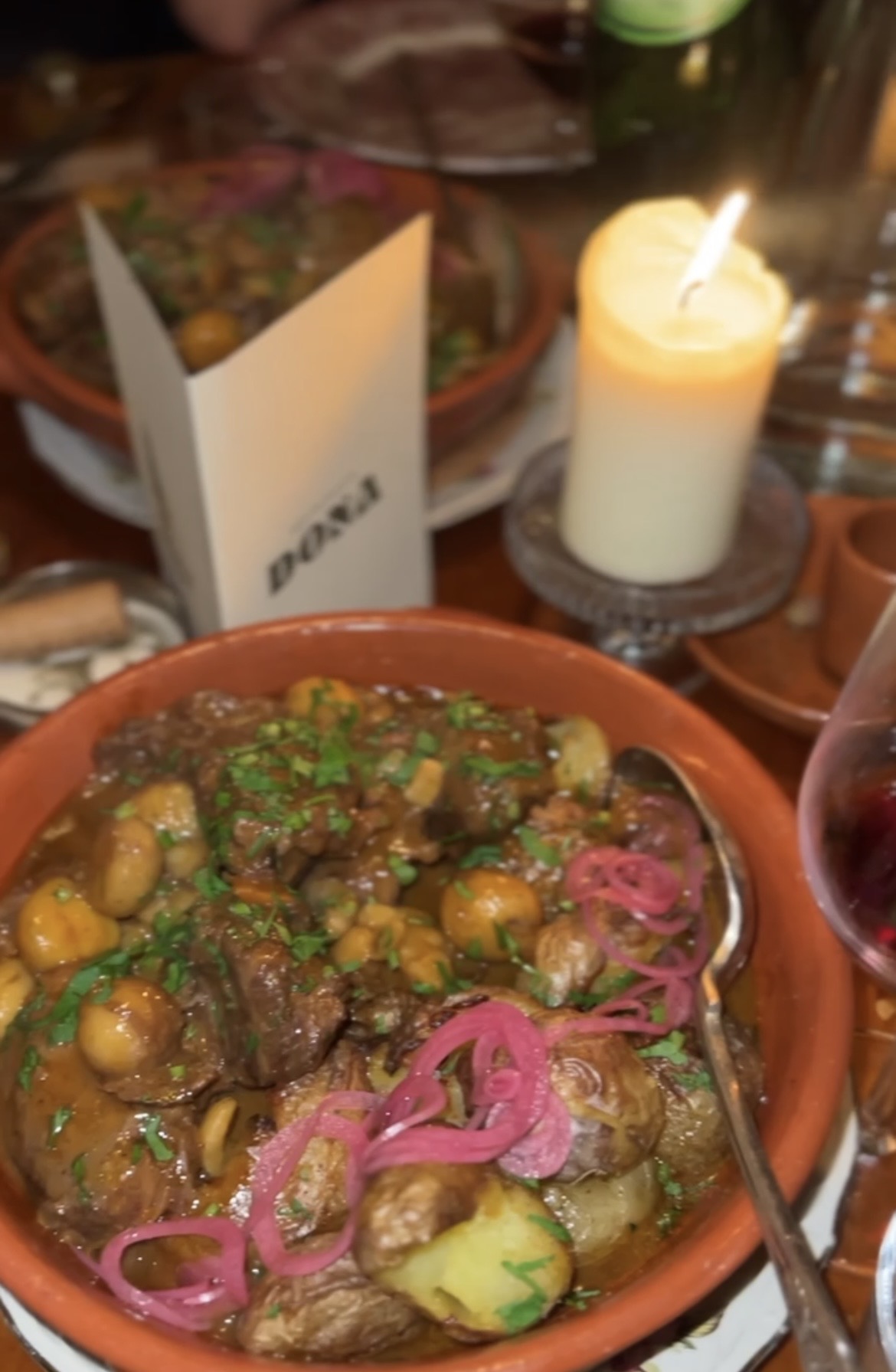 Hearty stew in a terracotta bowl by candlelight at a Sobremesa dinner