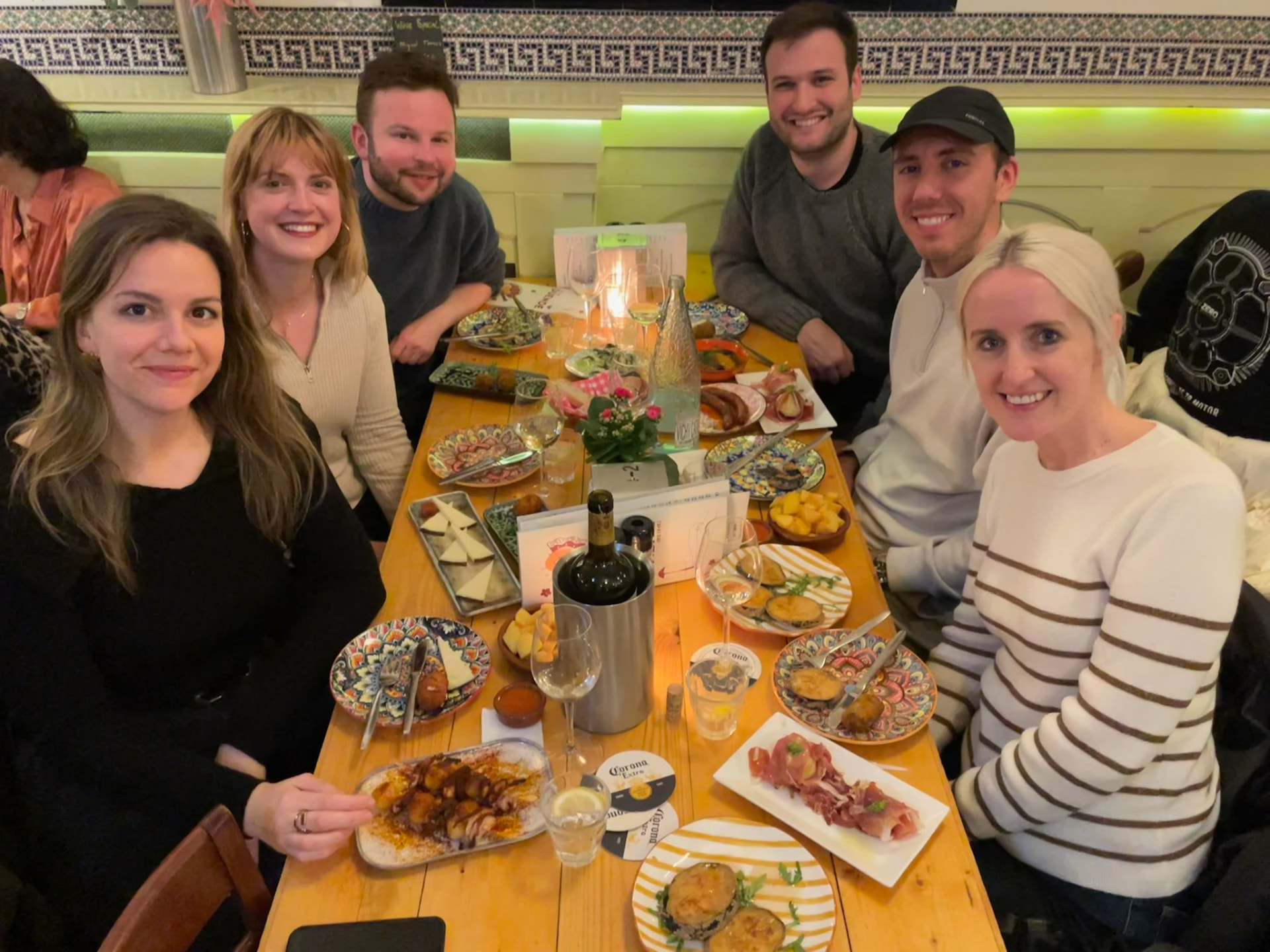 Six friends sharing tapas and wine around a wooden table at a Sobremesa dinner